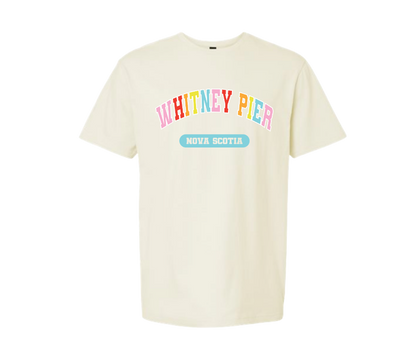 An off-white short-sleeve crewneck t-shirt featuring a colorful graphic on the chest that reads 'WHITNEY PIER' in multicolored letters and 'NOVA SCOTIA' in a light blue banner below it, displayed on a solid white background.
